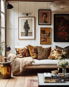 a living room filled with lots of furniture and pictures on the wall above it's windows
