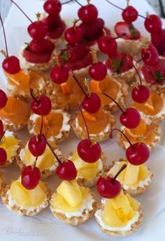 small appetizers are arranged on a plate with cherries and pineapples