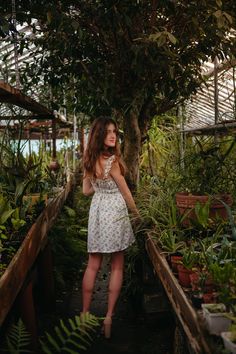a woman standing in a greenhouse with lots of plants