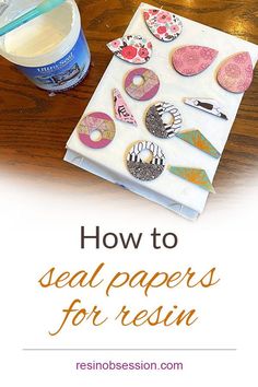 a wooden table topped with lots of crafting supplies and text overlay that reads how to seal papers for resin