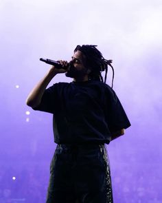 a man with dreadlocks on his head singing into a microphone at a concert
