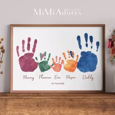 a family handprint is displayed in front of a vase with flowers on the shelf