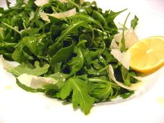 a white plate topped with greens and lemon wedges