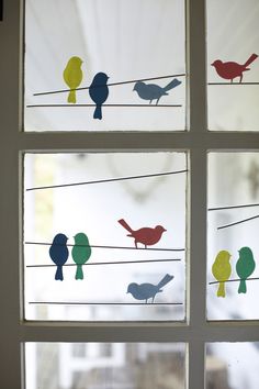 four different colored birds sitting on wires in front of a window with white frosted glass