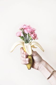 a person holding a banana with flowers in it