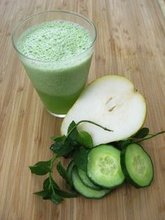 a green smoothie and sliced cucumbers on a cutting board