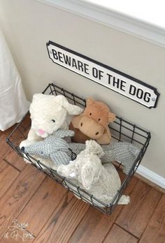 three stuffed animals in a wire basket on the floor next to a sign that says beware of the dog