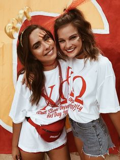 two girls with face paint posing for the camera in front of a large red and yellow sign