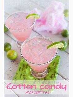 two glasses filled with pink margaritas on top of a green napkin next to limes