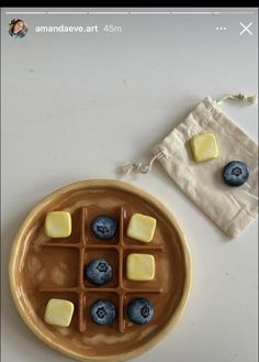 a plate with blueberries and cheese on it next to a small pouch of wax