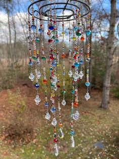 a wind chime hanging in the woods with lots of colorful beads and crystals on it