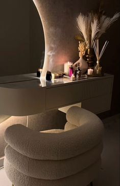 a white chair sitting in front of a mirror next to a table with candles and other items on it