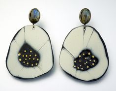 two white and black earrings with gold dots on them