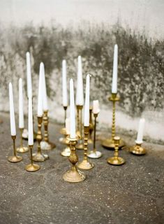 a bunch of candles that are sitting on the ground in front of a wall with no one around them