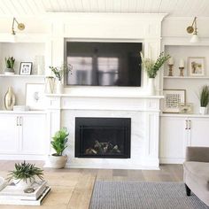 a living room with white furniture and a flat screen tv mounted above the fire place