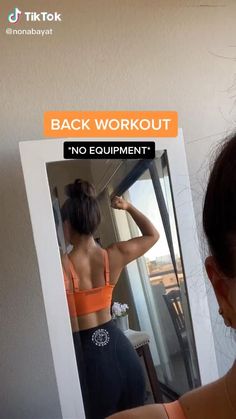 a woman in an orange top is looking at herself in the mirror with her back to the camera