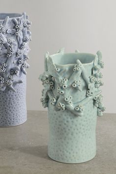 two blue vases with flowers on them sitting next to each other