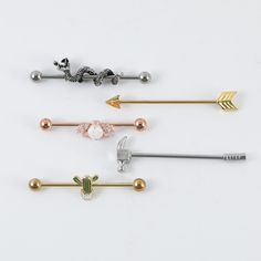 four different types of metal hair pins on a white surface with gold, silver, and green accents