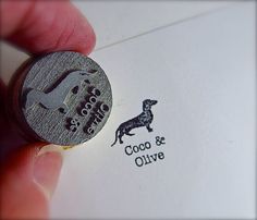 a close up of a person holding a stamp with a dog and name on it