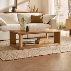 a wooden coffee table sitting on top of a rug in front of a white couch