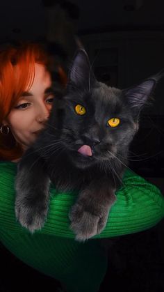 a woman with red hair holding a black cat in her arms and smiling at the camera