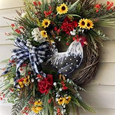 a wreath with a rooster and sunflowers hanging on the side of a house