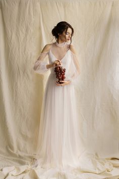 a woman in a white dress holding grapes