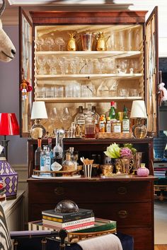 an old fashioned bar with wine glasses, liquor bottles and deer head on the top shelf