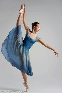 a young ballerina in a blue dress is performing