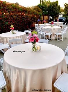 tables and chairs are set up outside for an event with flowers in vases on them