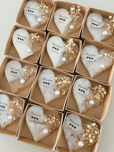 twelve white heart shaped ornaments in a box with gold foiled leaves and pearls on them