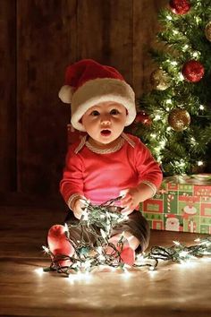 a baby is sitting in front of a christmas tree