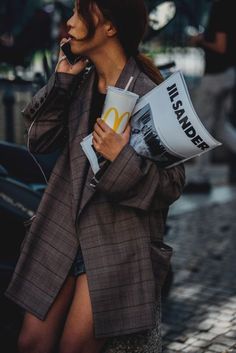 a woman is talking on her cell phone while holding a mcdonald's bag and coffee