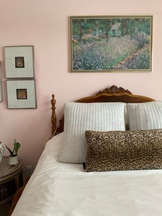 a bedroom with pink walls, white bedding and leopard print pillow cases on the headboard