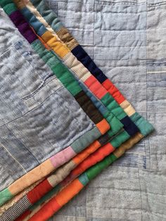 a pile of multicolored quilts laying on top of each other