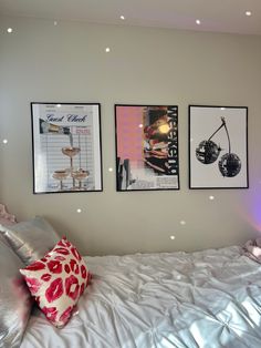 three framed pictures hang on the wall above a bed