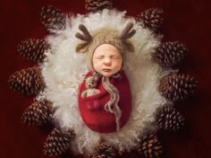 a baby is sleeping in a red blanket with pine cones on the head and legs