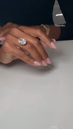 two hands holding each other on top of a white table with gold rings and bracelets