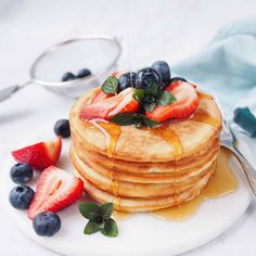 a stack of pancakes with syrup and fresh berries