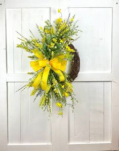 a wreath with yellow flowers hanging on a white door