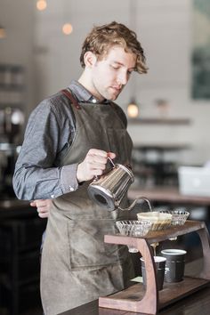 a man in an apron pours coffee into a cup