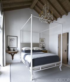 A chandelier by Maison Jansen, found in Argentina, hangs above a bed by Oly Studio in the master bedroom; the painting is by Andrew Bucci.   - ELLEDecor.com Dekoration, Quartos