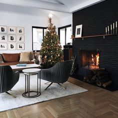 a living room filled with furniture and a fire place next to a christmas tree on top of a wooden floor