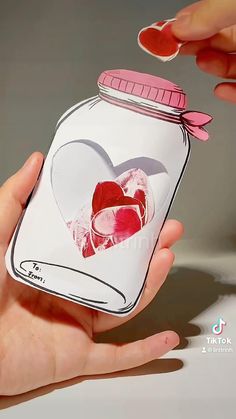 a hand holding a jar with hearts in it