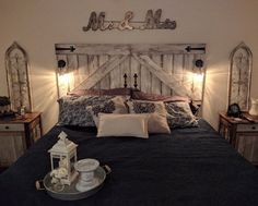 a bed with pillows and lights on the headboard is made up to look like an old barn door