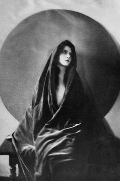 a black and white photo of a woman in a hooded cloak