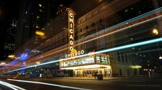 a theater marquee lit up at night with lights streaking across the street