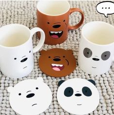 four mugs with faces painted on them sitting on a rug next to each other