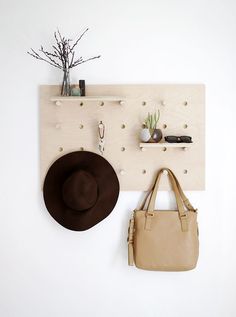 a hat and purse hanging on a wall next to a coat rack with hooks attached