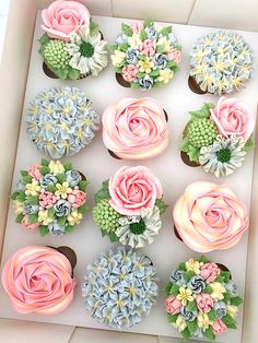 cupcakes decorated with pink and blue flowers in a box